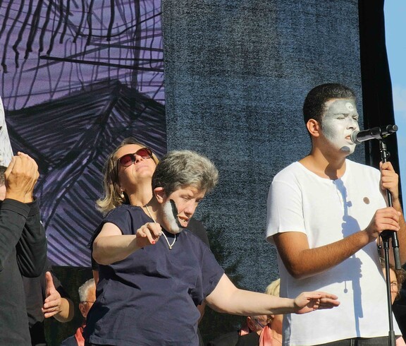 Menschen mit Gesichtsbemalung auf einer Bühne mit Mikrofon