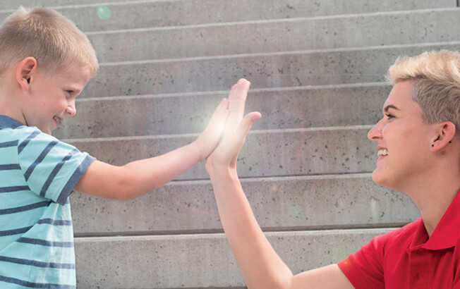 High-Five Kind und Caritas-Mitarbeiterin
