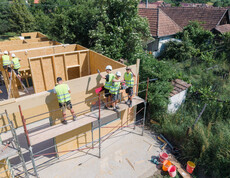 Arbeiter*innen helfen beim Bau eines Holzhauses