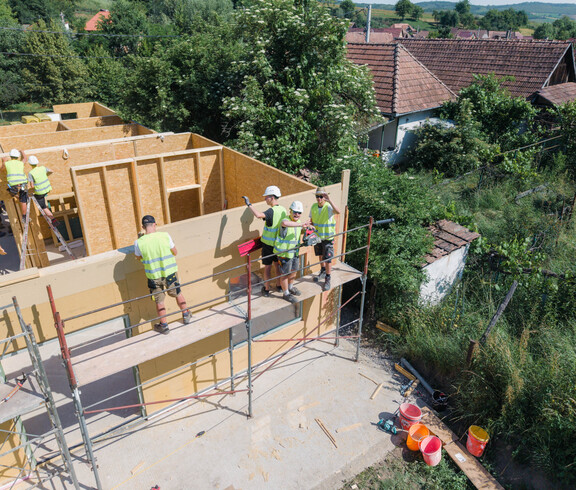 Arbeiter*innen helfen beim Bau eines Holzhauses