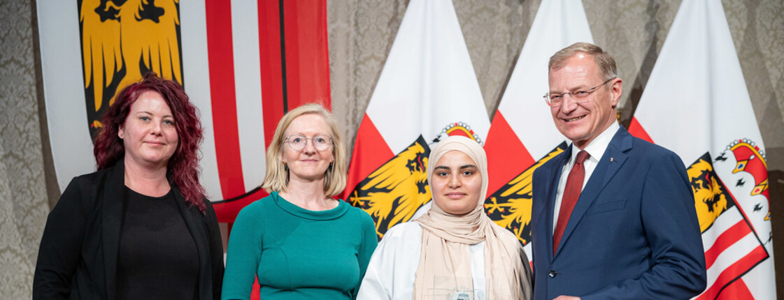 Drei Frauen und ein Mann stehen zusammen.