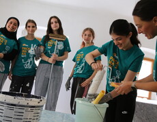 Sechs Jugendliche in der Halbtotalen mit Malutensilien in Vorbereitung die Wände zu streichen