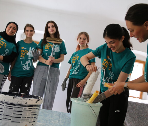 Sechs Jugendliche in der Halbtotalen mit Malutensilien in Vorbereitung die Wände zu streichen