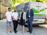 Drei Männer und eine Frau stehen vor einem Kleinbus mit der Aufschrift Help-Mobil.