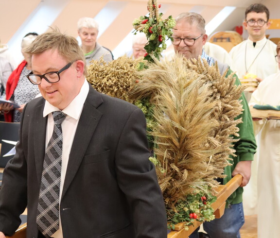 Zwei Männer tragen eine Erntekrone