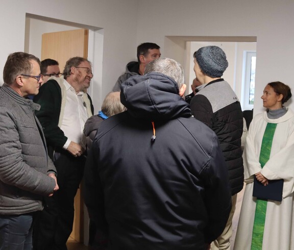 Viele Personen und die Seelsorgerin in einem neuen Haus.