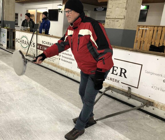 Ein Schütze setzt mit seinem Eisstock zum Schießen an. 