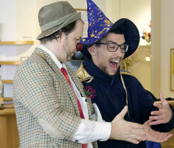 Clown mit roter Nase und junger Mann mit Zauberhut