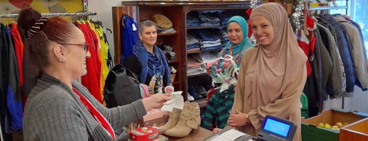 An der Kasse im Carla-Laden verkauft eine Frau einer Kundin Ware, im Hintergrund stehen zwei weitere Kundinnen