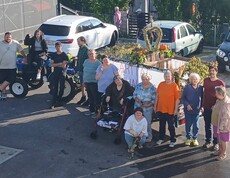 Viele Menschen stehen vor einem geschmückten Erntedankanhänger.