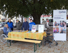 Mehrere Menschen vor einem Tisch mit Steinen und Rollup