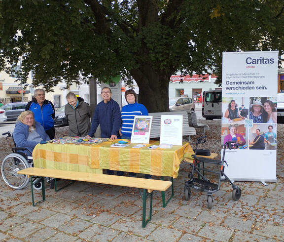 Mehrere Menschen vor einem Tisch mit Steinen und Rollup