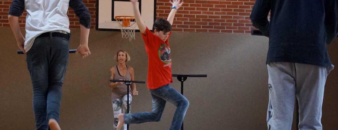 Kinder springen in einem Turnsaal auf Trampolin herum. 