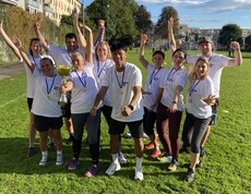 10 Personen in weißen Caritas-T-Shirts und Medaillien stehen am Spielfeld und freuen sich.