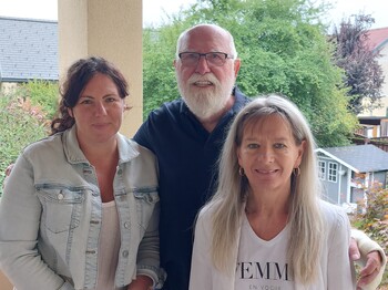 Drei Personen stehen im Freien.