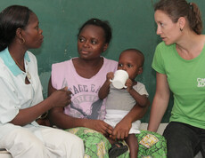 Vier Erwachsene im Gespräch, ein Kleinkind trinkt dabei aus einem Becher auf dem Schoß der Mutter