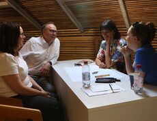 Vier Personen besprechen etwas und sitzen rund um einen Tisch.