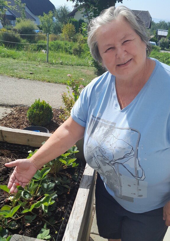 Frau steht neben Hochbeet.