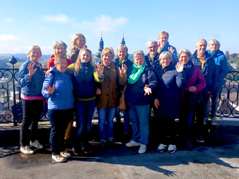 Eine Gruppe steht vor einer Kirche und winkt.