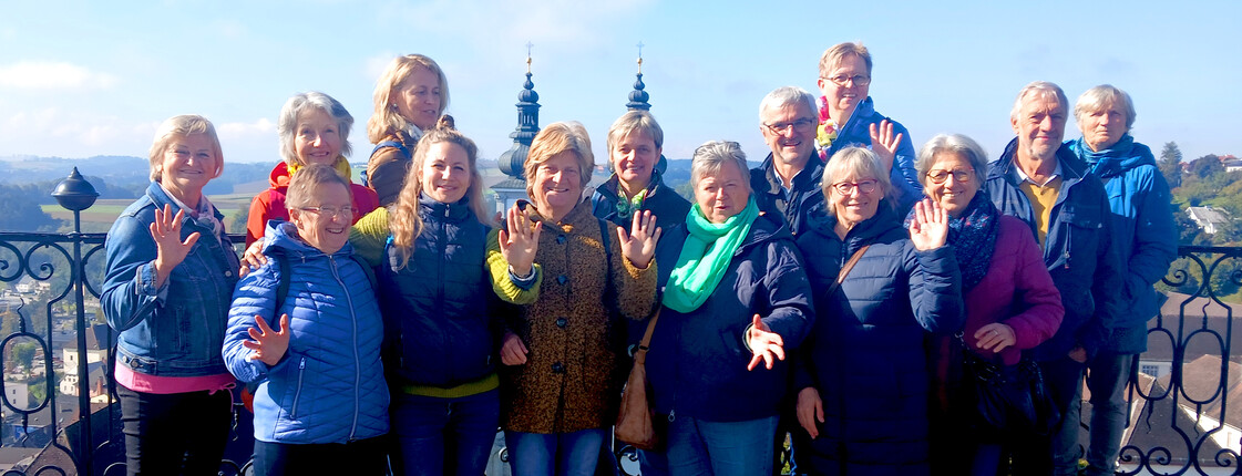 Eine Gruppe steht vor einer Kirche und winkt.