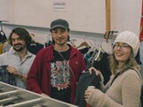 Drei junge Erwachsene sehen sich Kleidungsstücke an.