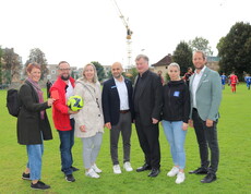 Sieben Personen stehen auf einem Fussballfeld im Freien.