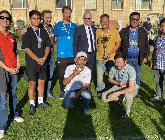 Mehrere Personen stehen am Fussballfeld zusammen.