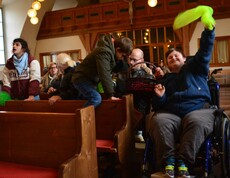 Bub im Rollstuhl schwingt ein gelbes Tuch