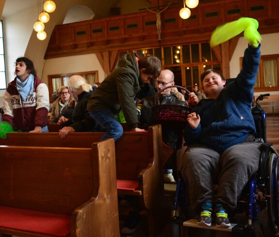 Bub im Rollstuhl schwingt ein gelbes Tuch