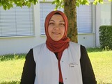 Frau mit rotem Kopftuch und einer weißen Caritas Pflege Weste