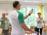Ein Sportwissenschafter macht Bewegungsübungen mit zwei Seniorinnen.