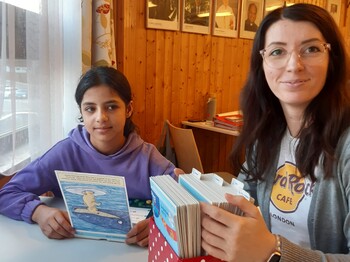 Freiwillige wie Yvonne Wituschek unterstützen die Kinder im Lerncafé. Wer mitmacht, bewegt viel – für andere und für sich selbst. Ein Kind und eine Frau sitzen am Tisch und lernen.