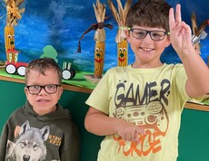 Zwei Jungs stehen nebeneinander, einer von ihnen macht das Peace Zeichen und grinst in die Kamera