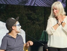 Mann mit weißer Gesichtsbemalung auf einer Bühne mit einer Frau im weißen Shirt.