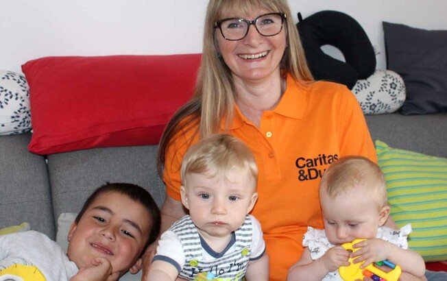 Eine Frau sitzt mit drei Kindern auf der Couch