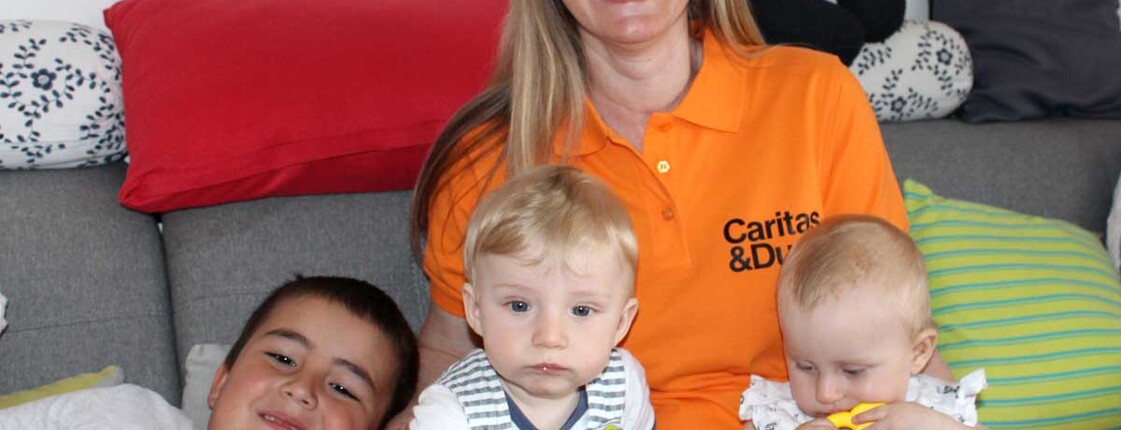 Eine Frau sitzt mit drei Kindern auf der Couch