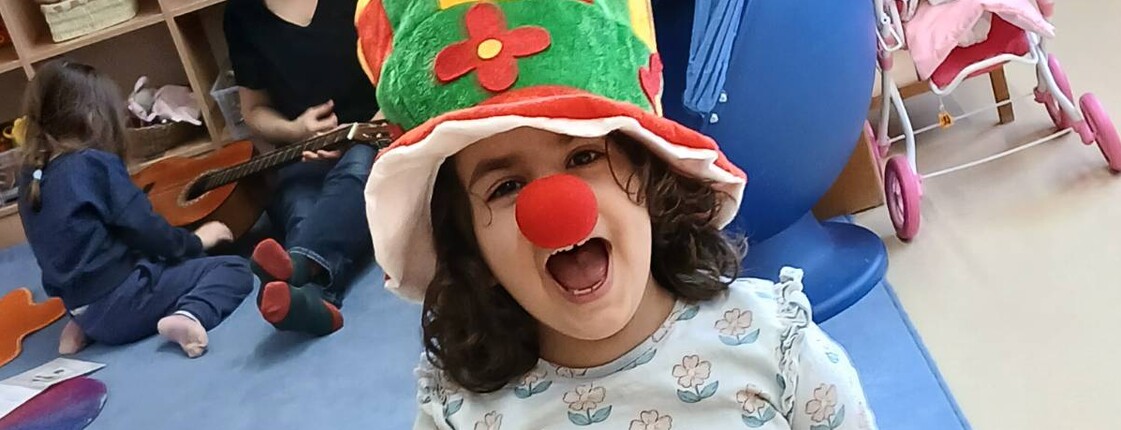 Mädchen mit Clownhut und roter Nase