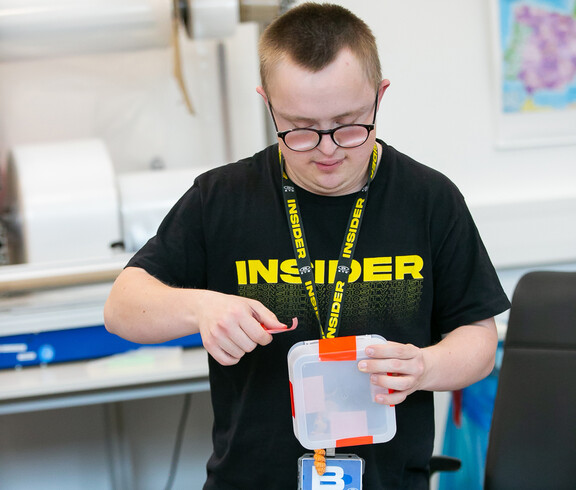 Mann im schwarzen T-Shirt mit gelber Schrift "INSIDER" beim Arbeiten