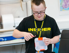 Mann im schwarzen T-Shirt mit gelber Schrift "INSIDER" beim Arbeiten