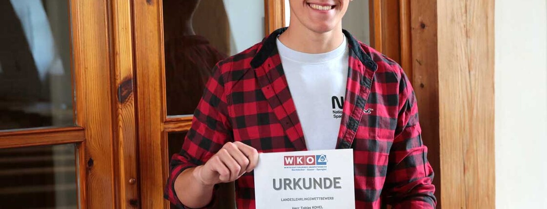 Tobias Kohel hält eine Urkunde in der Hand