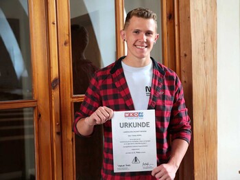 Tobias Kohel hält eine Urkunde in der Hand