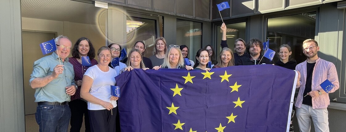 Gruppenbild: Personen halten eine Europaflagge 