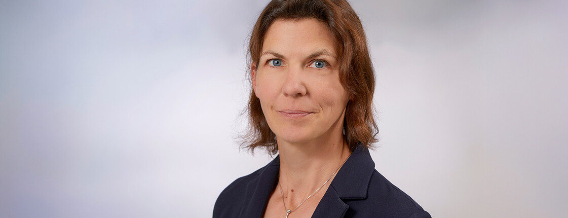 Eine Frau mit Schulterlangen braunen Haaren, einem Sakko und T-Shirt im Portrait