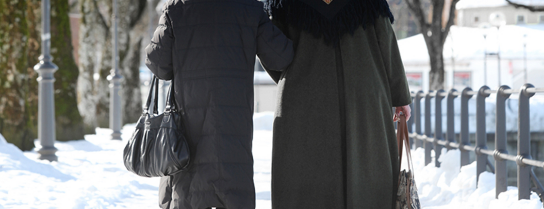 Zwei ältere Frauen laufen einen voll geschneiten Weg entlang