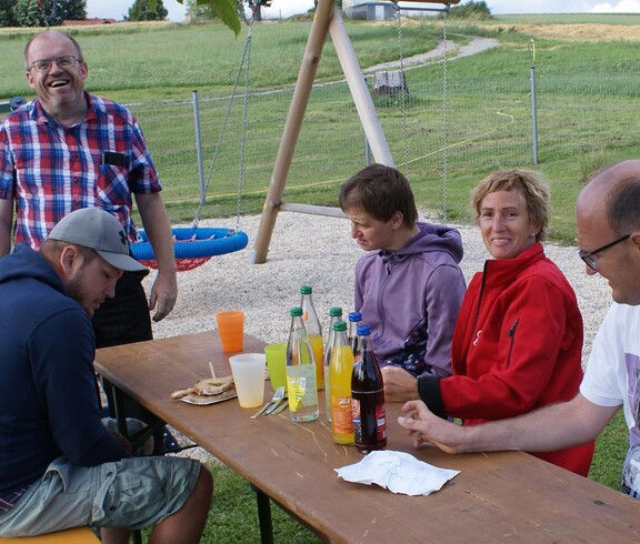 Leute sitzen an einem  Holztisch beim Feiern.