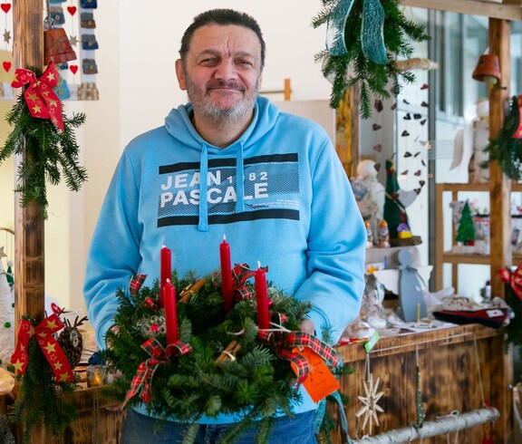 Mann hat Adventkranz in der Hand