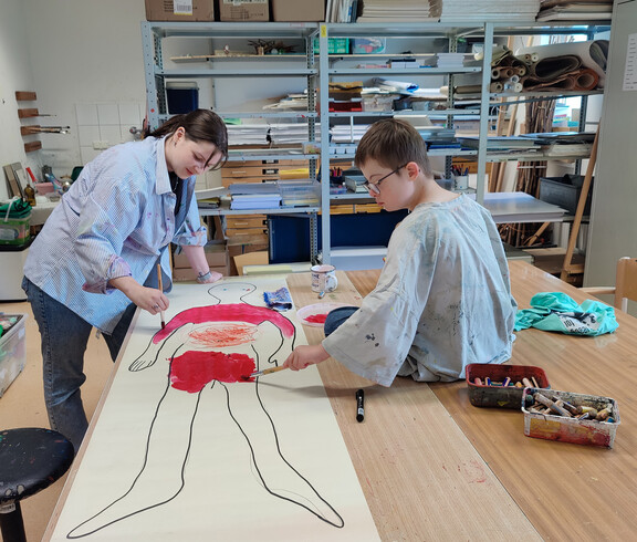 Zwei Frauen malen Bild einer körpergroßen Person