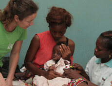 Eine Mutter hält ihr unterernährtes Baby, während eine Krankenschwester den Armumfang des Kindes misst