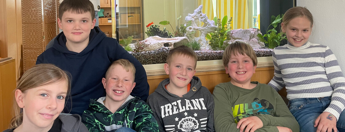 Kinder sitzen auf einer Couch im Hintergrund sieht man das Aquarium