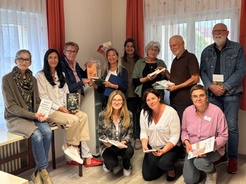 Eine Gruppe Erwachsener schaut in die Kamera und jeder hält ein Buch in der Hand